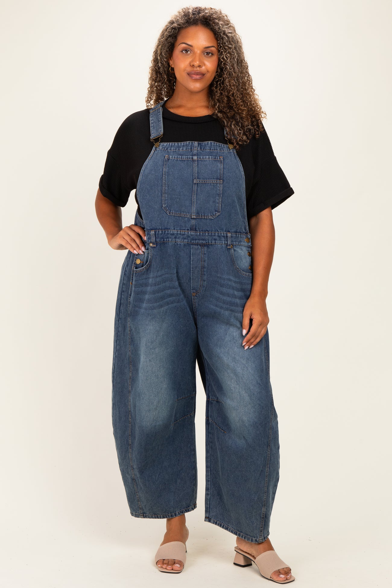 woman wearing a black oversized t-shirt and blue denim plus size overalls with wide legs