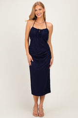 woman wearing a navy blue halter neck midi dress with ruching detail and a front tie, standing and smiling