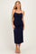 woman wearing a navy blue halter neck midi dress with ruching detail and a front tie, standing and smiling