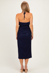 woman wearing a navy blue halter neck dress with a fitted bodice and a midi length, viewed from the back
