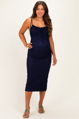 woman wearing a navy blue lace maternity dress with thin straps and a fitted silhouette highlighting her baby bump