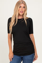 woman wearing a black ribbed top with short puff sleeves and a ruched waist, paired with blue jeans