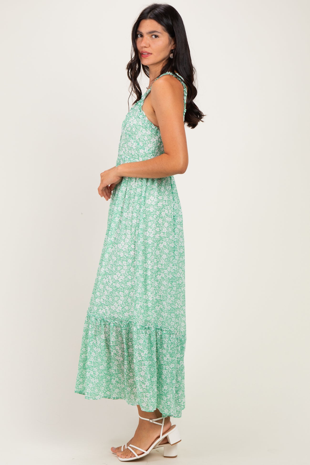 woman wearing a green floral maxi dress with adjustable straps and a tiered skirt