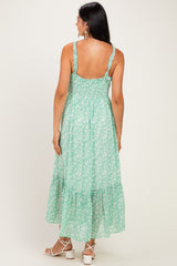 woman wearing a back view of a green floral maxi dress with ruffled straps and a tiered hem