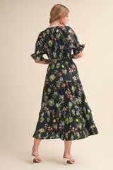 woman wearing a black floral maxi dress with ruffled sleeves and tiered skirt, viewed from the back