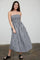 woman wearing a black and white gingham strapless maxi dress and black slide sandals