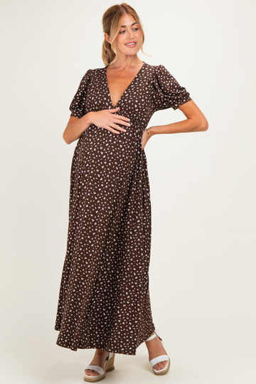 woman wearing a brown polka dot maternity maxi dress and posing with her baby bump visible