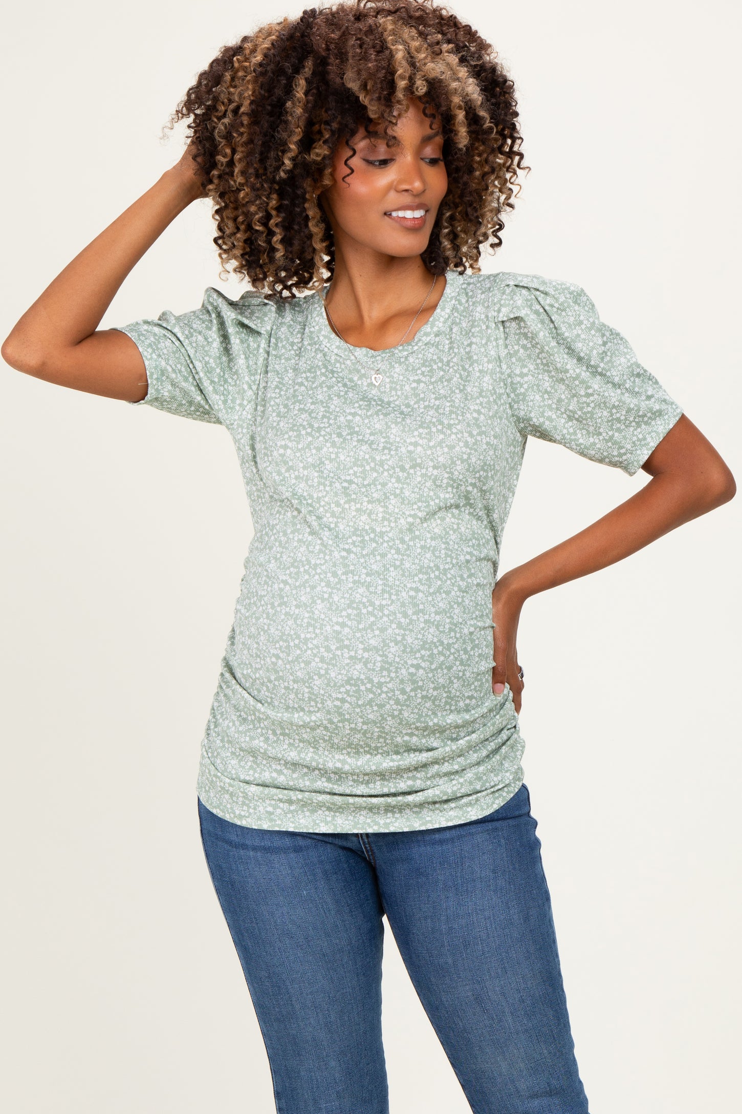 woman wearing a green floral maternity top with puff sleeves and a visible baby bump