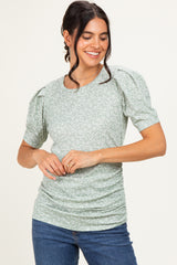 woman wearing a green floral puff sleeve shirt with ruching and a relaxed fit, paired with blue jeans
