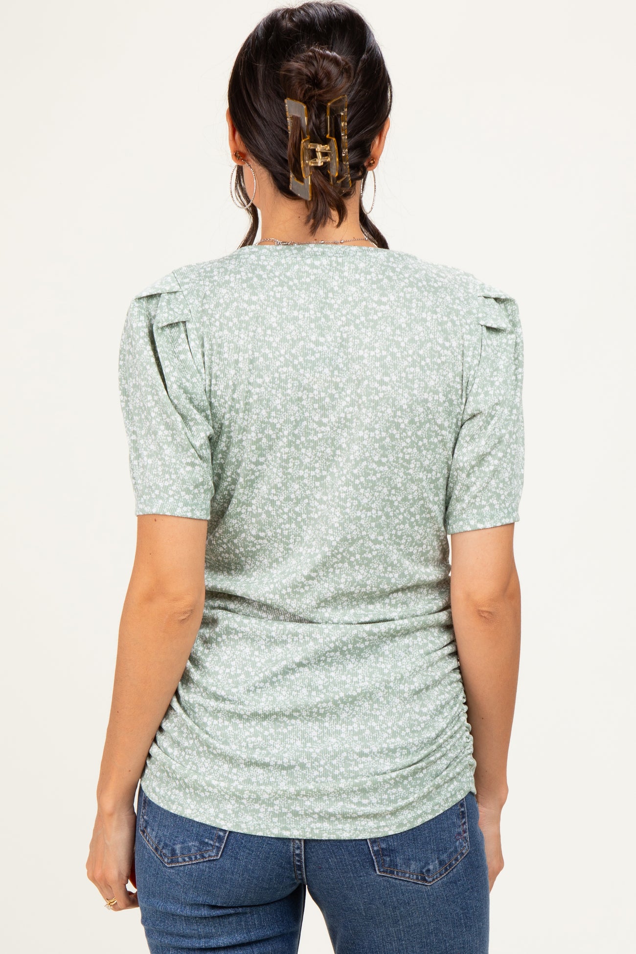 woman wearing a green floral short sleeve top with ruched sides and puff sleeves, shown from the back