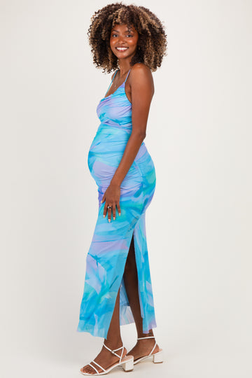 woman wearing a blue tropical print maternity dress with side slit and ruching, showcasing her baby bump