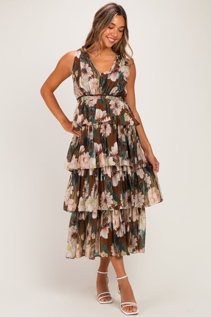 woman wearing a floral patterned maternity dress with a tiered design and v-neckline, smiling against a light background