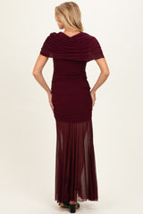 woman wearing a burgundy maternity gown with ruched bodice and sheer maxi skirt, showing a baby bump from the back