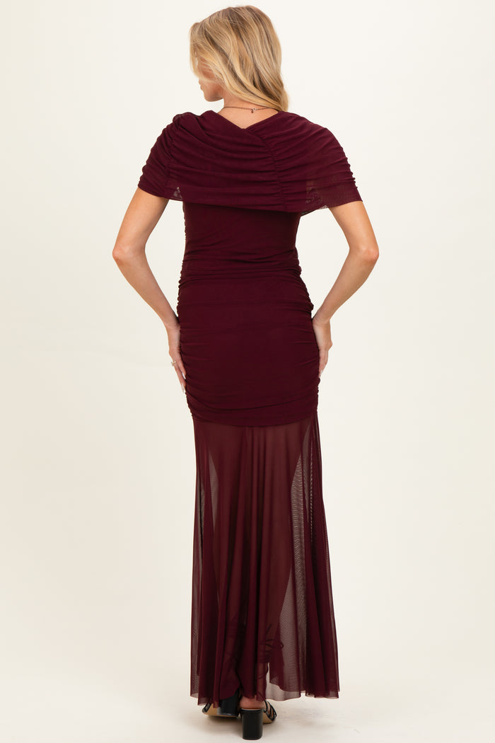 woman wearing a burgundy maternity gown with ruched bodice and sheer maxi skirt, showing a baby bump from the back
