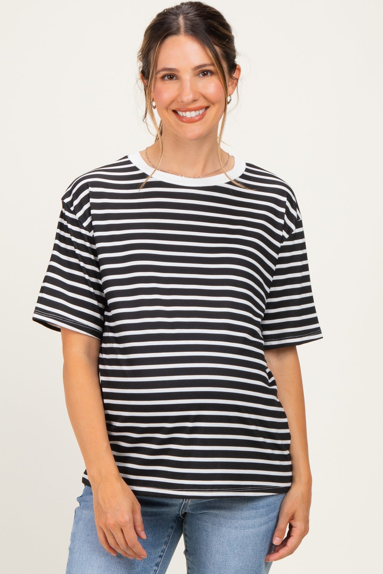 woman wearing a black and white striped maternity top with short sleeves and a relaxed fit, baby bump visible