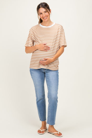 woman wearing a striped tan and white maternity t-shirt and holding her baby bump with light blue jeans