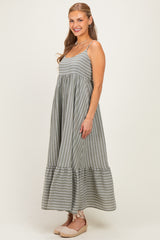 woman wearing a gray striped maxi dress with a tiered hem and thin straps, posed in a light-filled setting