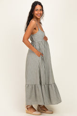 woman wearing a green and white striped maternity maxi dress with pockets and a visible baby bump