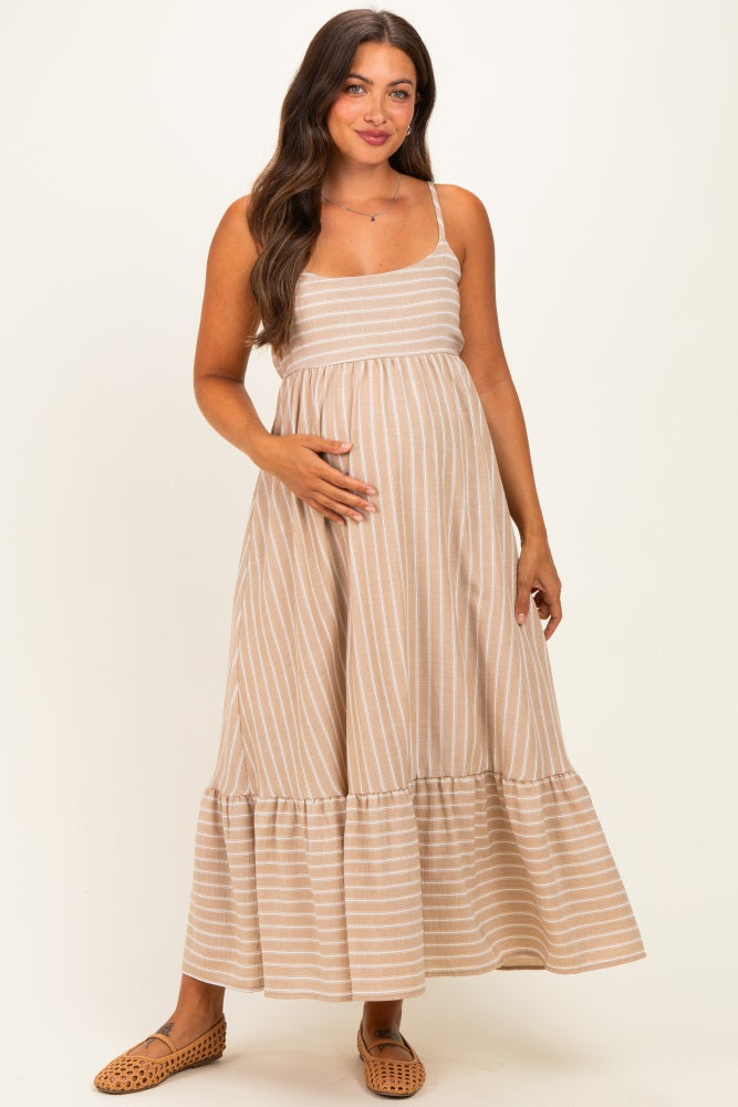 woman wearing a beige striped maternity maxi dress with a tiered hem and holding her baby bump