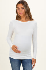 woman wearing a white long sleeve maternity top and holding her baby bump
