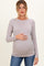 woman wearing a light purple ribbed maternity top, gently cradling her baby bump, paired with blue jeans