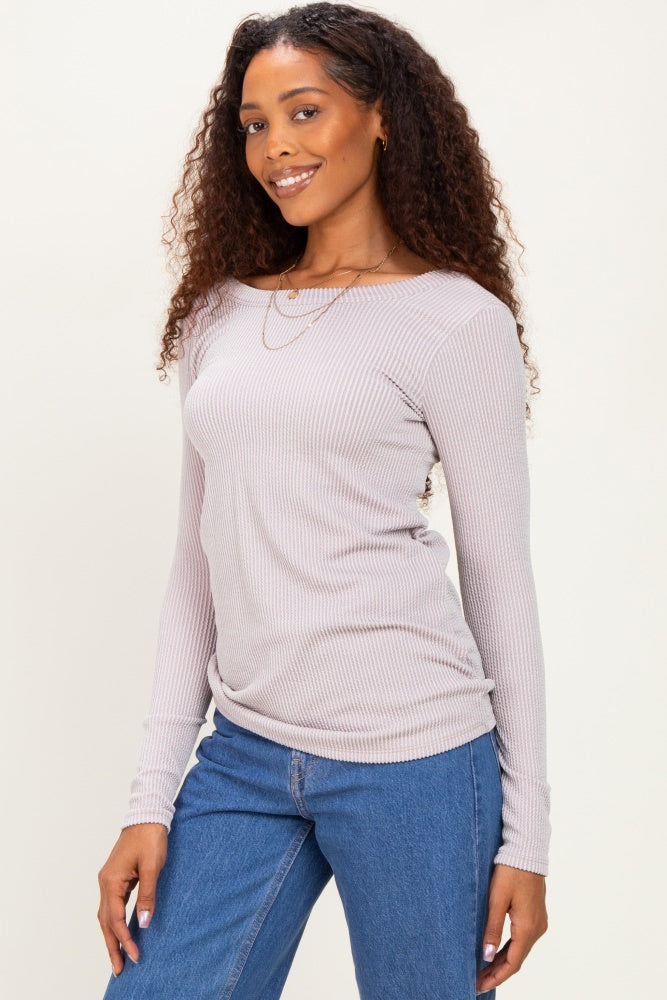 woman wearing a light lavender long sleeve ribbed top paired with blue jeans, smiling and posing to the side