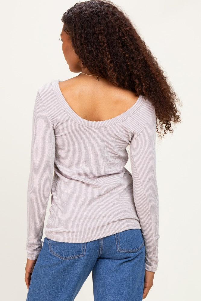 woman wearing a light lavender ribbed long sleeve top with an open back, styled with high-waisted jeans