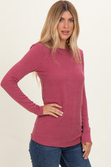 woman wearing a pink ribbed long sleeve top with side button detailing and fitted sleeves