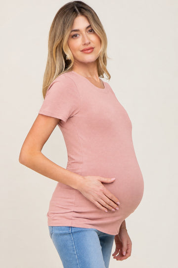 woman wearing a soft pink maternity t-shirt and holding her baby bump
