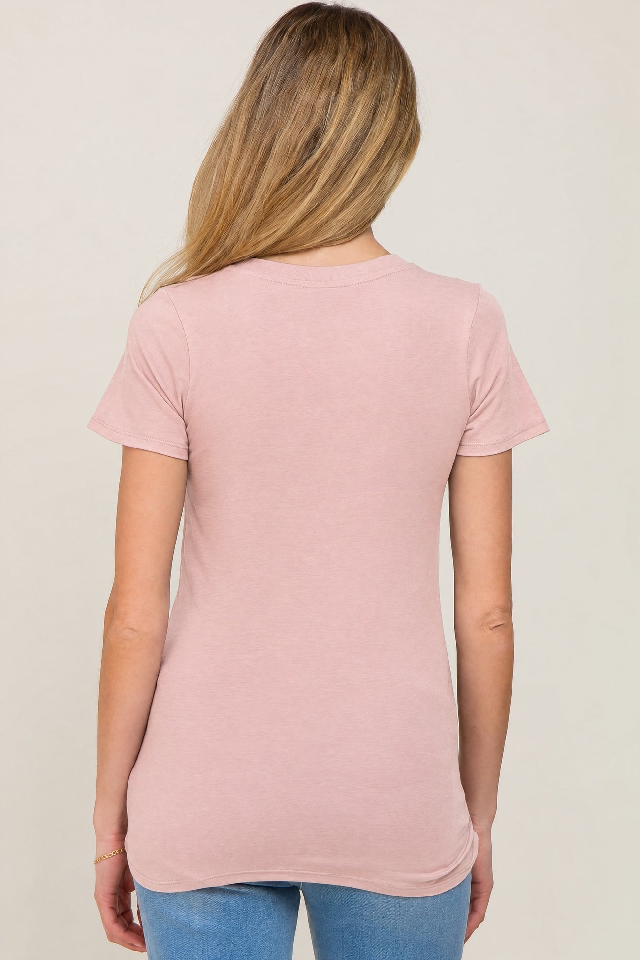 woman wearing a light pink short sleeve maternity top, viewed from the back