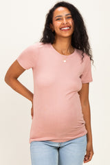woman wearing a pink short sleeve maternity top with a visible baby bump