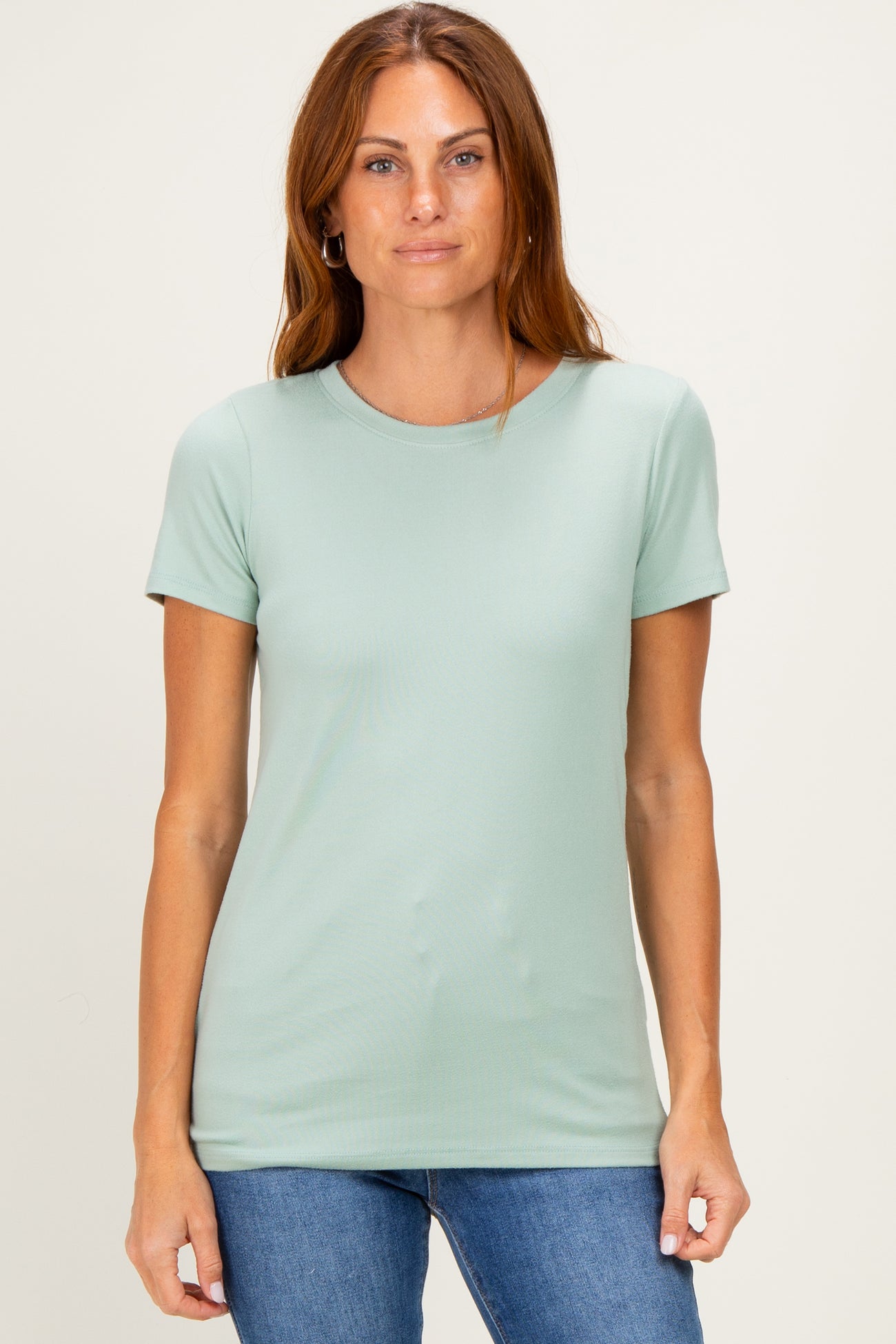 woman wearing a light green short sleeve t-shirt paired with blue jeans