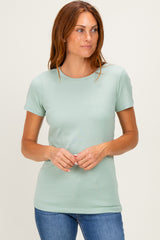 woman wearing a light green short sleeve t-shirt with a round neckline and a relaxed fit, standing against a neutral background