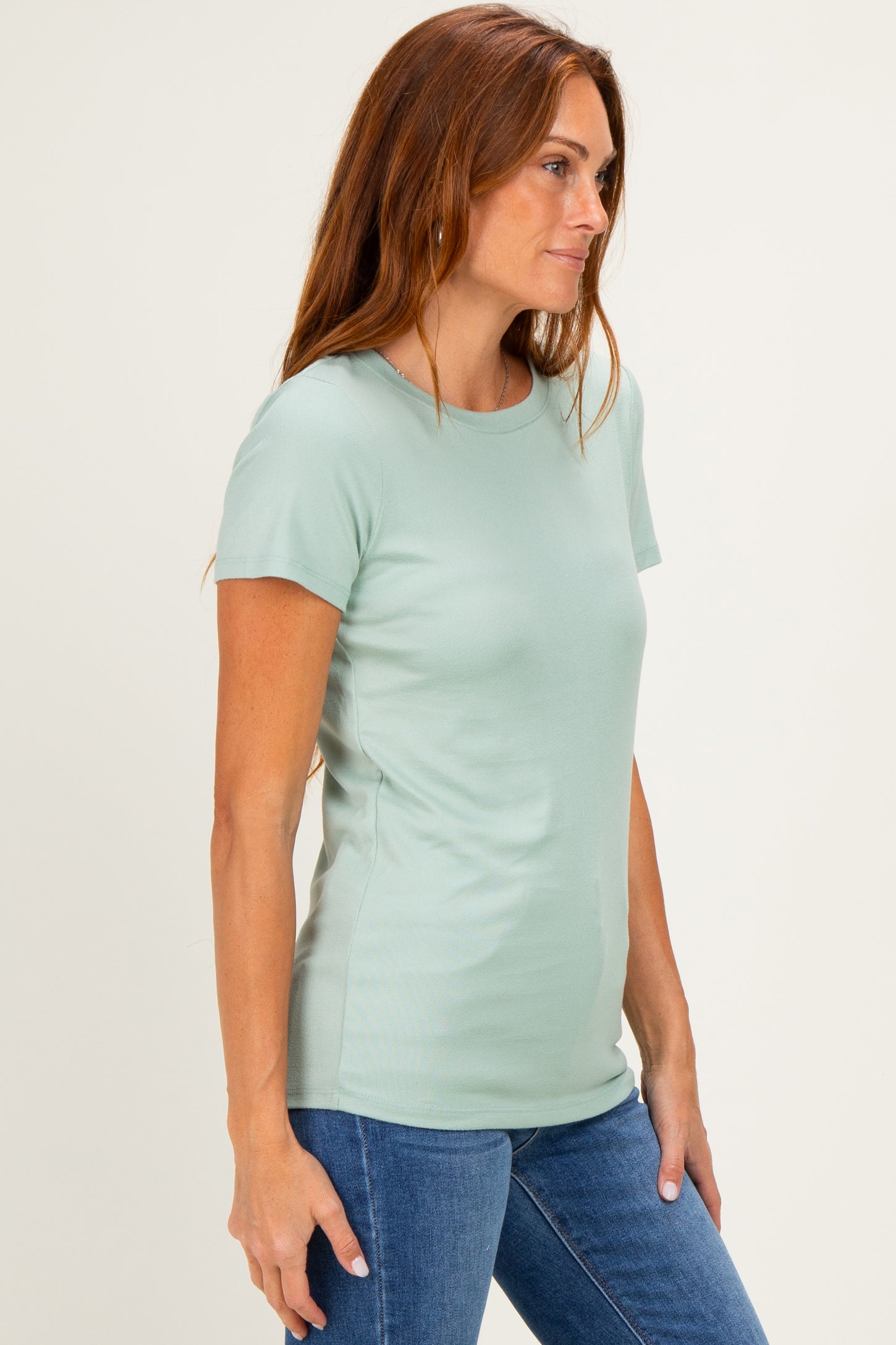 woman wearing a light green short sleeve fitted t-shirt and blue jeans