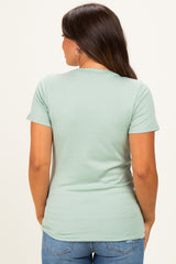 woman wearing a mint green short sleeve maternity top, seen from the back