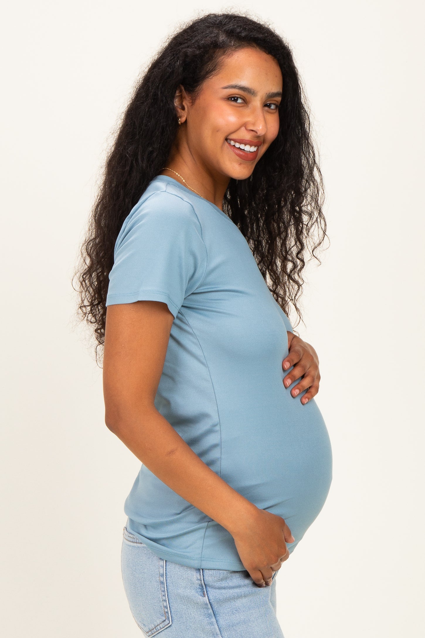 woman wearing a light blue maternity t-shirt and holding her baby bump