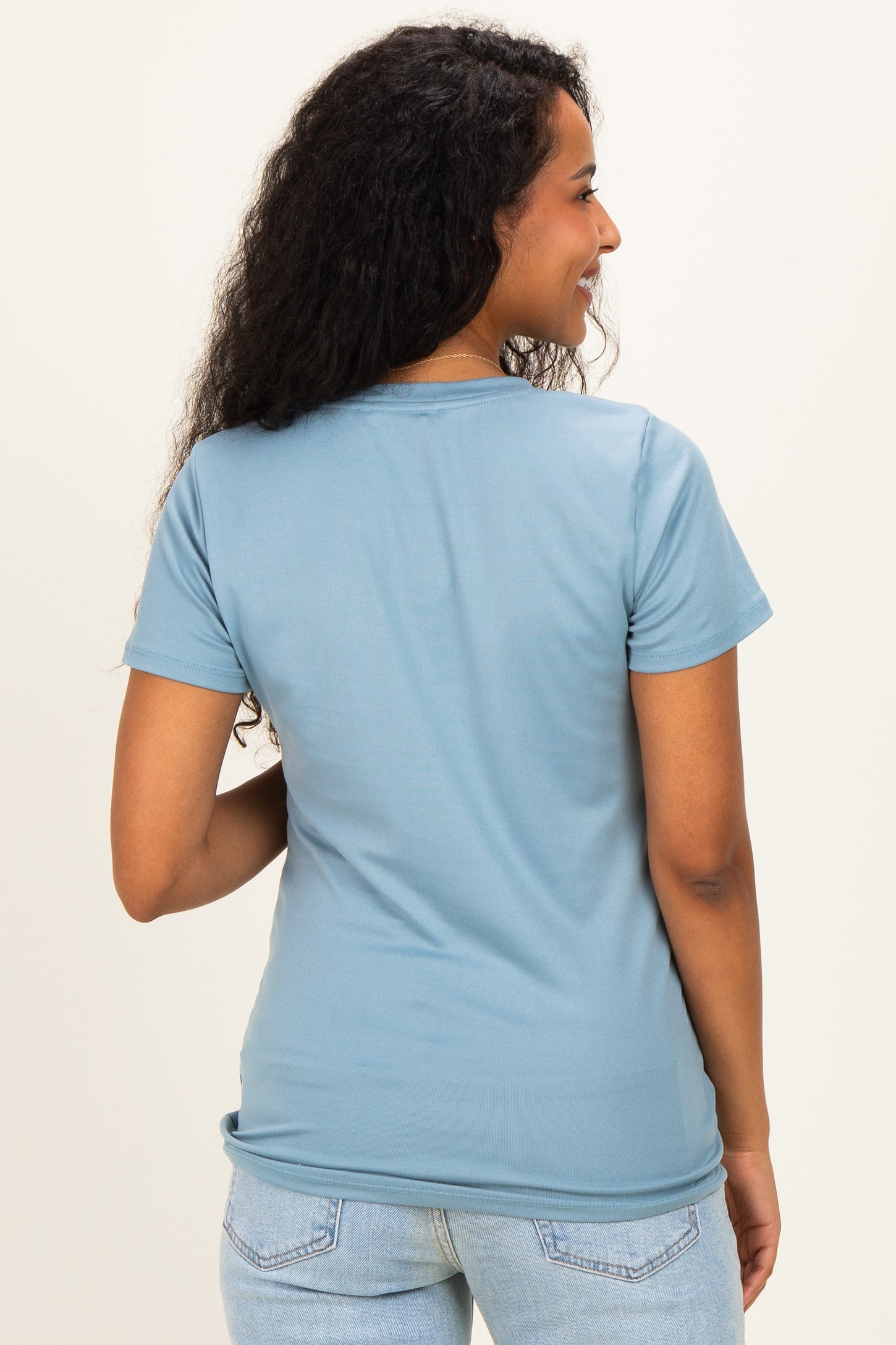 woman wearing a light blue maternity t-shirt, seen from the back.