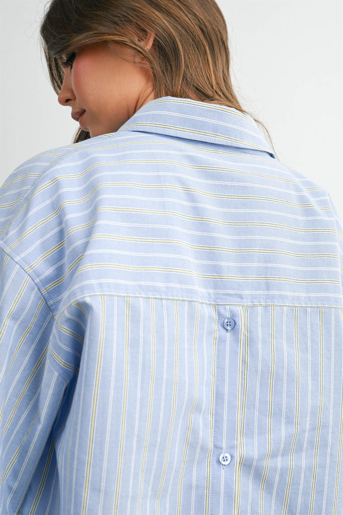woman wearing a light blue striped button-up shirt, showcasing the back detail and collar style