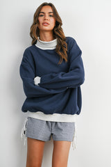 woman wearing a navy oversized sweatshirt with a light grey collar and matching gingham shorts
