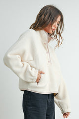 woman wearing a cream-colored fleece pullover jacket with a half-zip and pink details