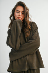 woman wearing an oversized brown striped long sleeve top with a relaxed fit and rolled cuffs