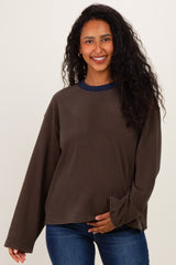 woman wearing a brown striped maternity sweatshirt with a navy collar and holding her baby bump