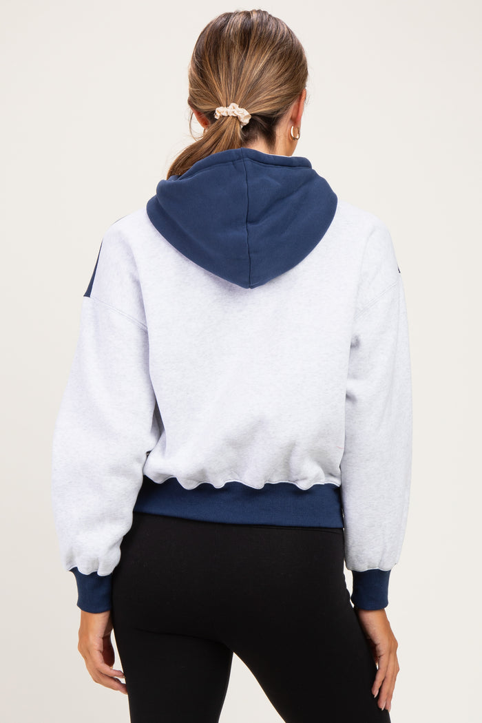 woman wearing a gray and navy maternity hoodie with a cropped fit and balloon sleeves, seen from the back