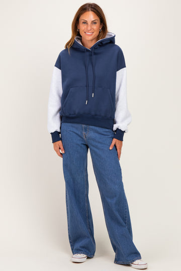 woman wearing a navy and gray color-block hoodie with a front pocket and blue wide-leg jeans