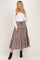 woman wearing a white long sleeve top and a brown and white checkered maxi skirt with a tie waist