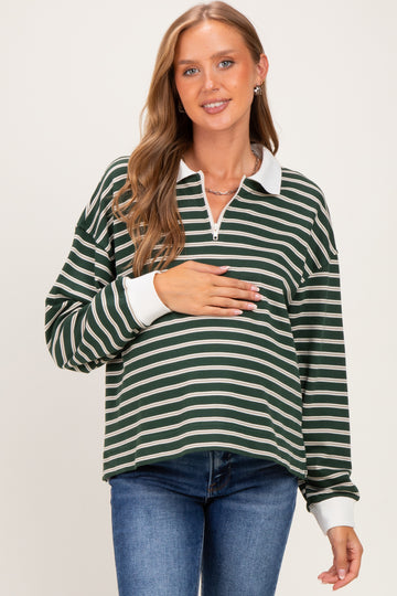 woman wearing a green and white striped maternity pullover with a half zipper, holding her baby bump