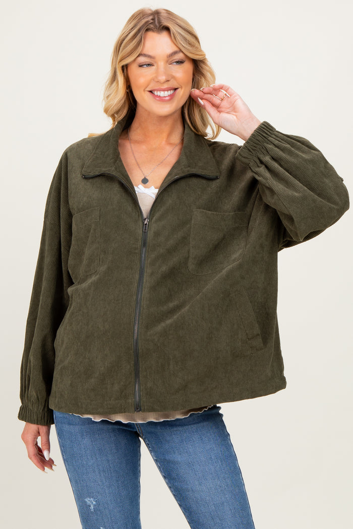 woman wearing a dark green corduroy zip-up jacket with balloon sleeves and front pockets over a beige top and jeans