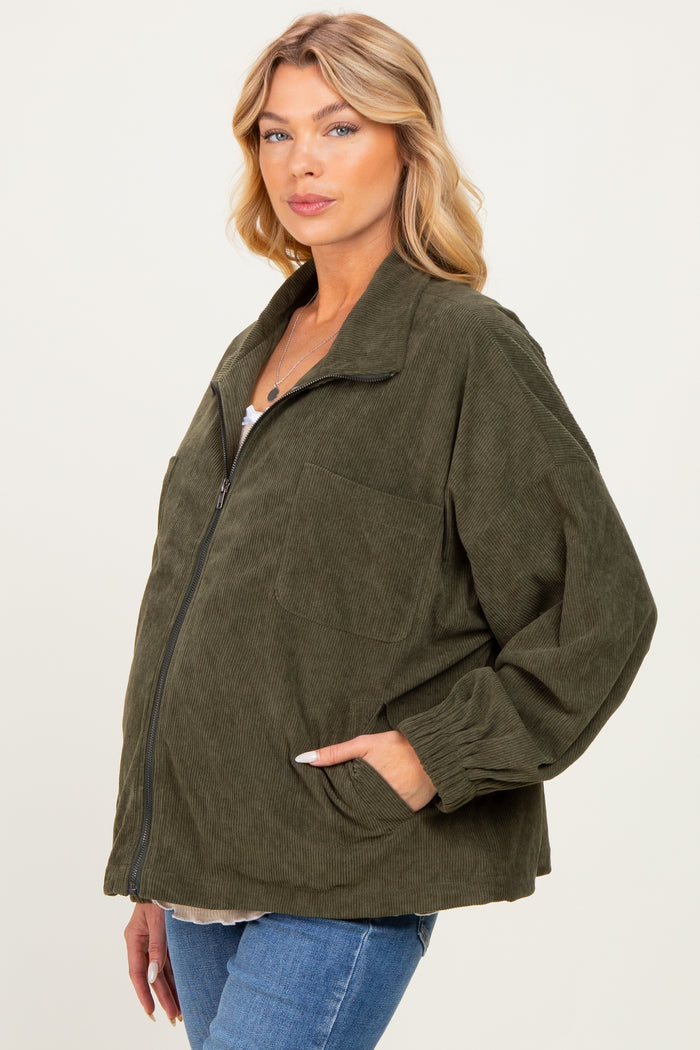 woman wearing a dark green corduroy maternity jacket with a oversized fit and front pocket, displaying her baby bump