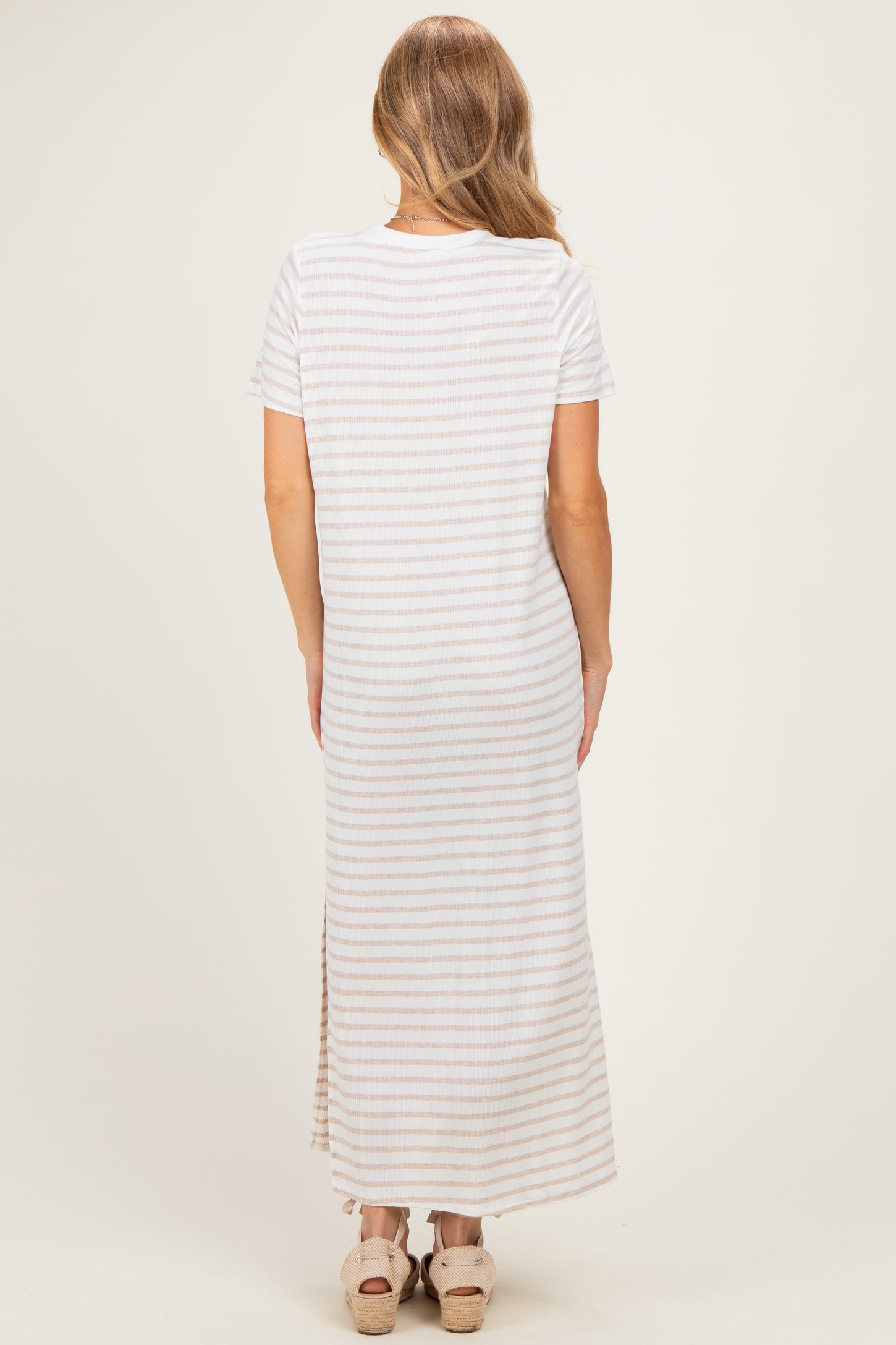 woman wearing a striped maxi dress with short sleeves and a side slit, viewed from the back
