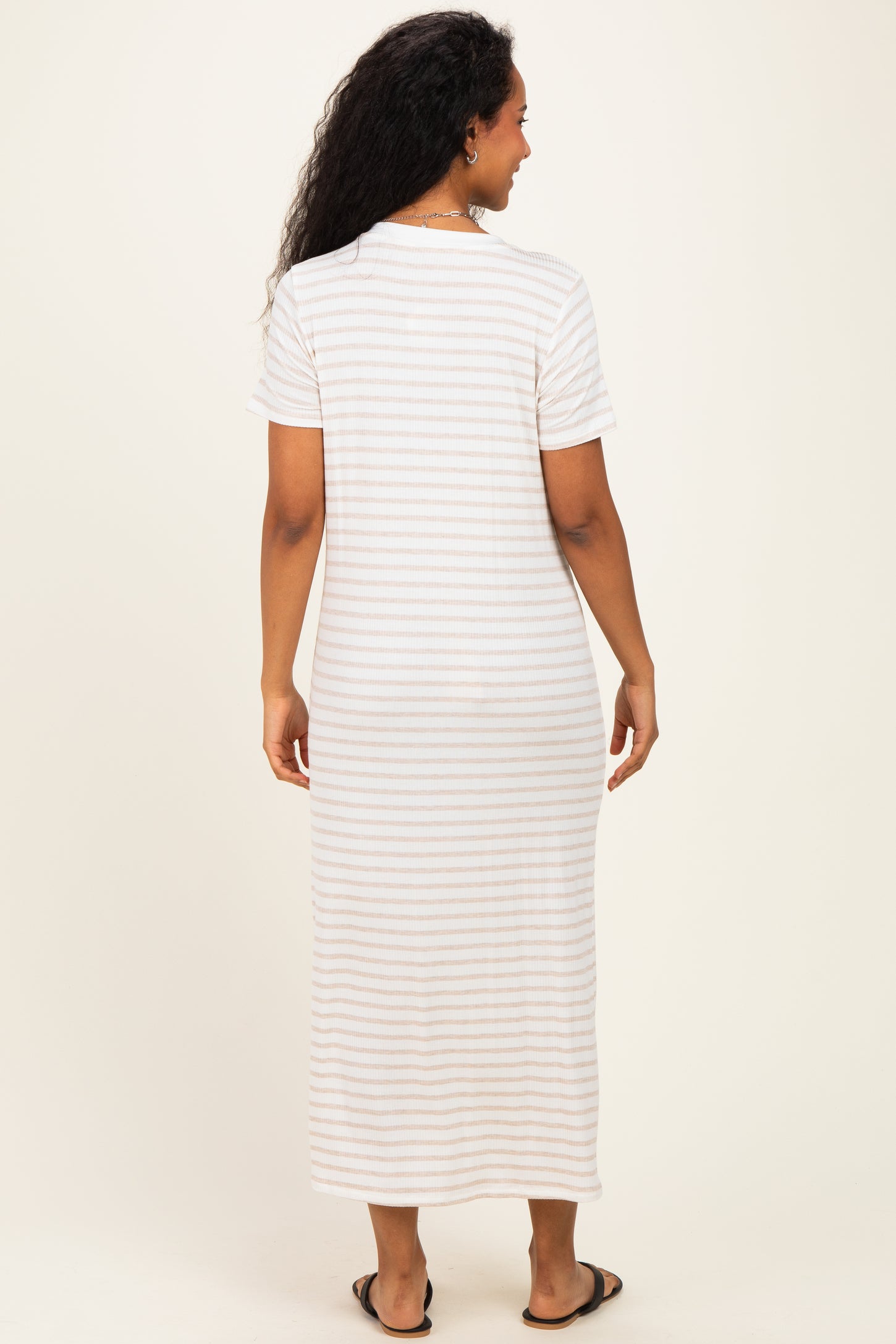 woman wearing a striped white and beige maternity maxi dress, showing a relaxed fit from the back